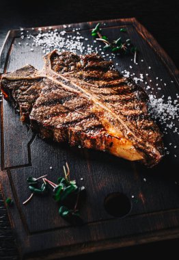 Koyu arka planda tahta tahtada ızgara biftek.