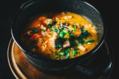 Pirinçli et çorbası ve ahşap masa arkasında sebzeler.