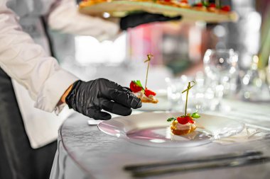 Garsonun elinde kanepe var. Restoran servisi. Açık büfe ya da yemek servisi.