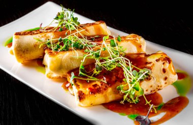 İnce krep ruloları, tabakta kıyma, ahşap masa üzerinde koyu arkaplan.