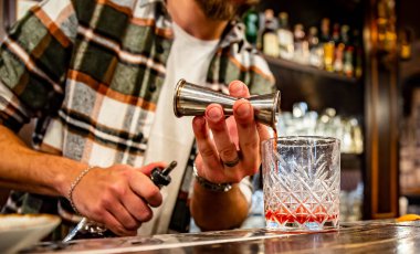 Barmen el barmeni barda cam negroni kokteyli yapıyor.