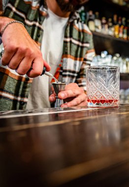 Barmen el barmeni barda cam negroni kokteyli yapıyor.