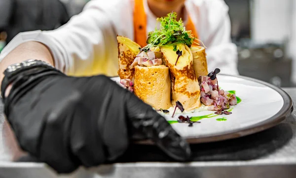 手袋料理のシェフの手薄切りパンケーキクレープポテトにニシンの魚を詰めキッチン ストック写真