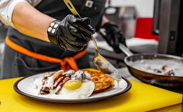 Chef Händer Handskar Matlagning Stekt Pannkaka Med Svamp Sås Bacon Stockbild