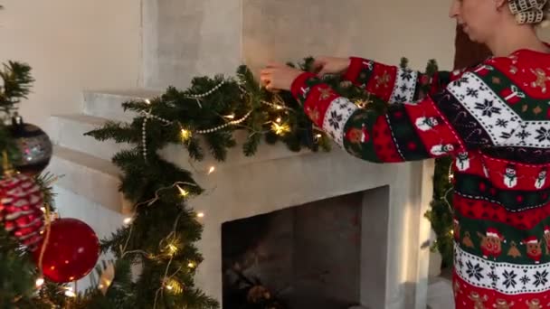 Femme décore cheminée de Noël en pull avec un motif de Noël — Video