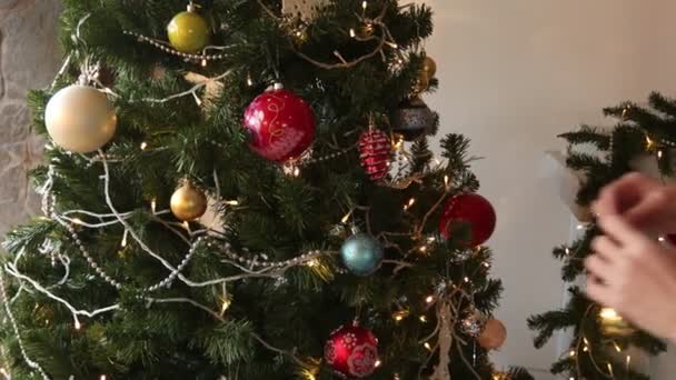 Donna sta decorando l'albero di Natale in maglione con un modello di Natale — Video Stock