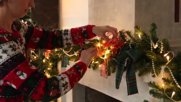 Kvinna är dekorera jul öppen spis i tröja med en jul mönster — Stockvideo