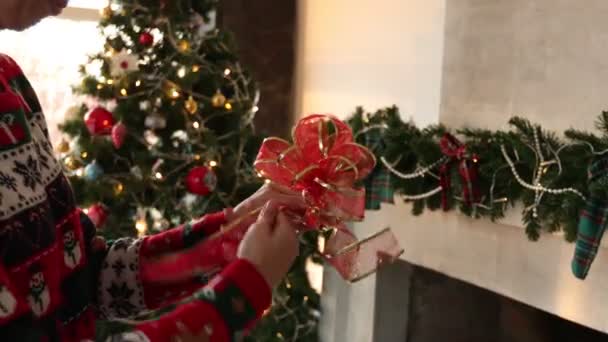 Молодая женщина в свитере с рождественским рисунком делает рождественское украшение — стоковое видео