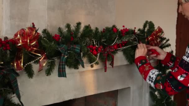 Kvinna är dekorera jul öppen spis i tröja med en jul mönster — Stockvideo