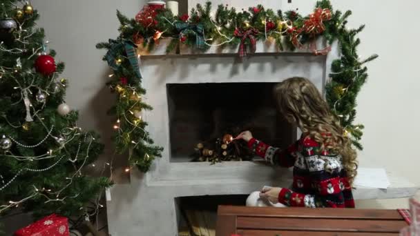 Noel desenli süveter giyen genç bir kadın şömineyi yakıyor. — Stok video