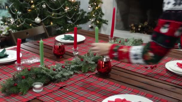 Νεαρή γυναίκα σε πουλόβερ με χριστουγεννιάτικο σχέδιο διακοσμημένο το τραπέζι της Πρωτοχρονιάς — Αρχείο Βίντεο