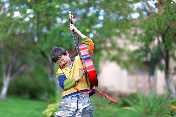 Musik student spela gitarr och sjunga utomhus Stockfoto