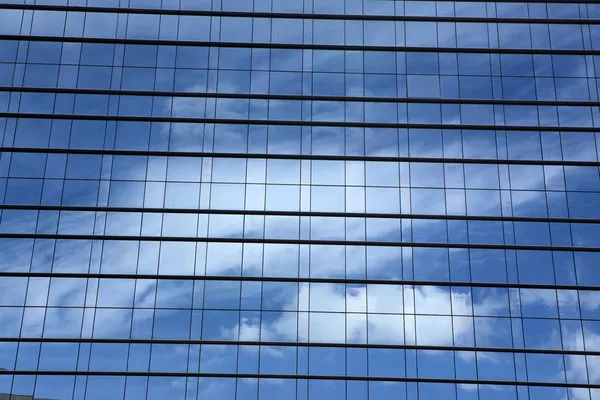 Hemel en wolken weerspiegeld in windows van moderne kantoorgebouw — Stockfoto