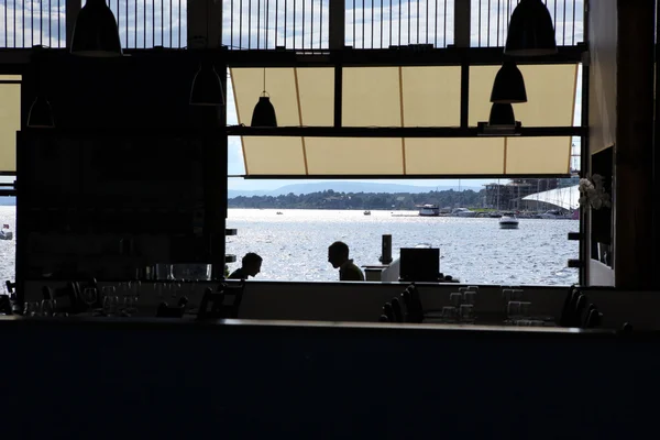 Café escuro vazio com duas silhuetas e vista para a baía do mar, foc — Fotografia de Stock