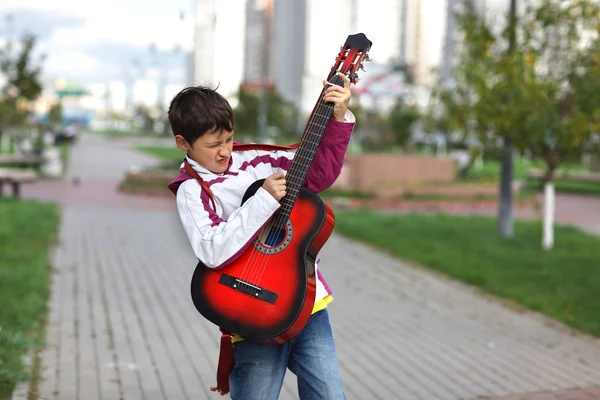 Мальчик играет на гитаре на улице — стоковое фото