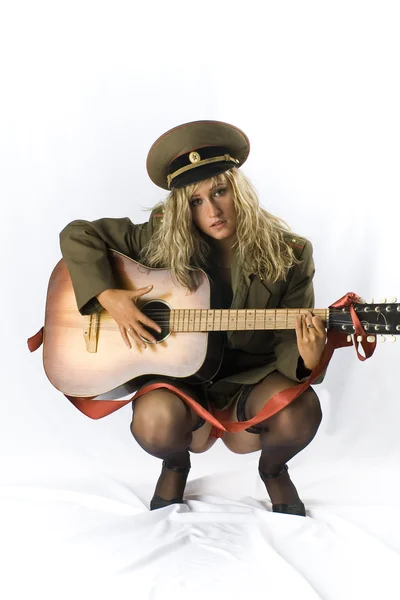 Blondine in alter sowjetischer Militärform und schwarzen Strümpfen posiert im Studio mit traditioneller russischer Akustikgitarre — Stockfoto