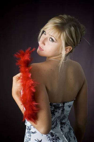 Rubia con abanico de plumas rojas sobre fondo negro — Foto de Stock