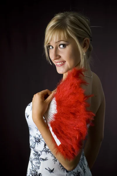 Rubia con abanico de plumas rojas sobre fondo negro —  Fotos de Stock