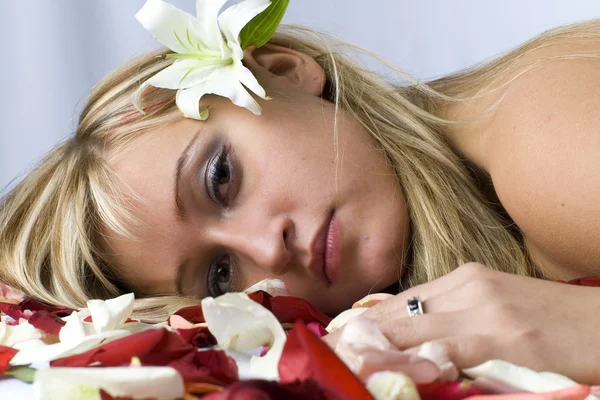 Милая блондинка с обнаженными плечами, покрытая лепестками роз. — стоковое фото