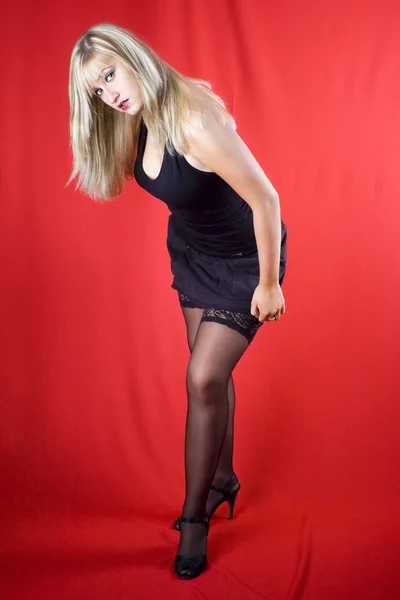 赤い背景の上に黒のドレスでブロンディ — ストック写真
