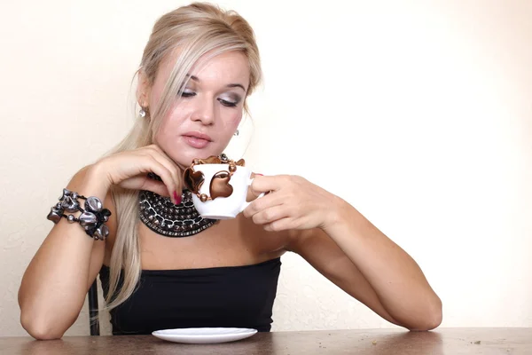 Mujer con taza de chocolate contra la pared amarilla en la mesa — Foto de Stock