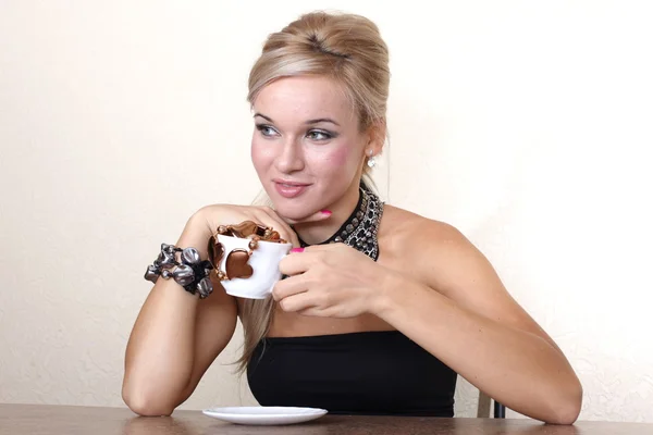 Mujer con taza de chocolate contra la pared amarilla en la mesa — Foto de Stock