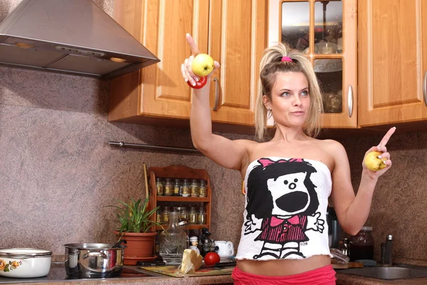 Красива молода жінка тримає яблуко на кухні — стокове фото