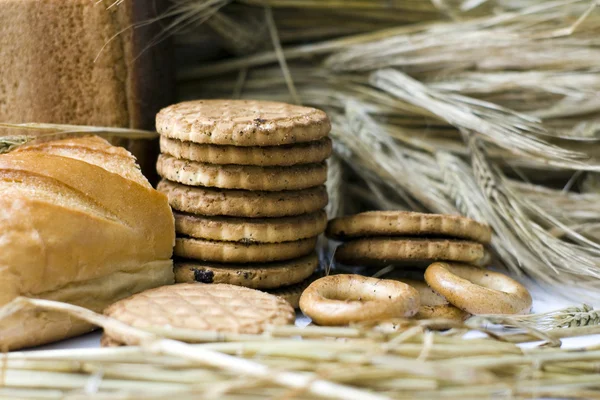 Wheat ears, bagels, cookies and bread on wooden table — Stock Photo, Image