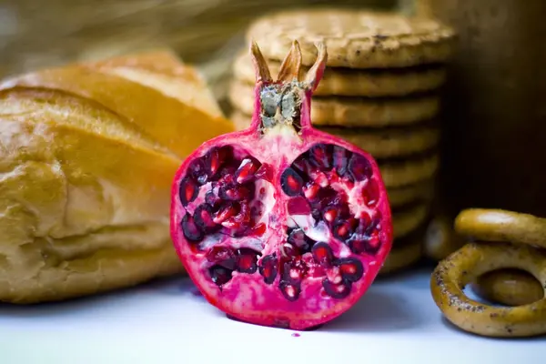 Wheat ears, Fresh pomegranate, cookies and bread bagels on wooden table — Stock Photo, Image