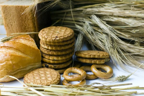 Wheat ears, bagels, cookies and bread on wooden table — Stock Photo, Image