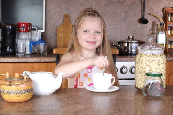 Little girl drinks tea from cup at kitchen — Stock Photo, Image