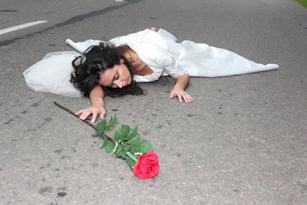 Невеста с розой лежит на дороге — стоковое фото