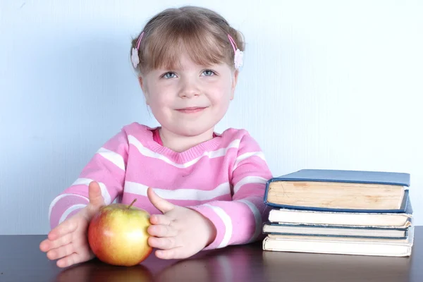 Kleines Mädchen mit Apfel und Büchern — Stockfoto