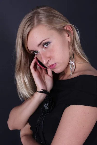 Портрет красивой блондинки разговаривающей по телефону на черном фоне — стоковое фото