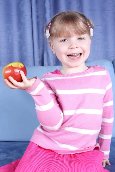 Kitap kanepe ve elma ile sürpriz küçük kız — Stok fotoğraf
