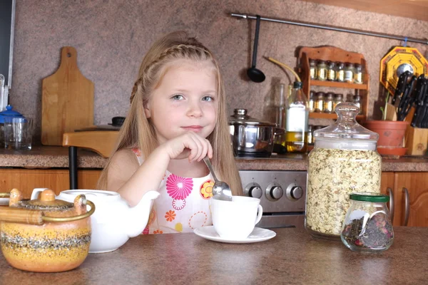 Little girl drinks tea from cup at kitchen — Stock Photo, Image