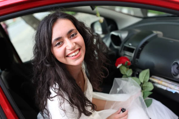 Noiva com uma rosa sentar em um carro — Fotografia de Stock