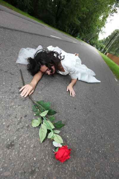 Hermosa novia acostada en un camino — Foto de Stock