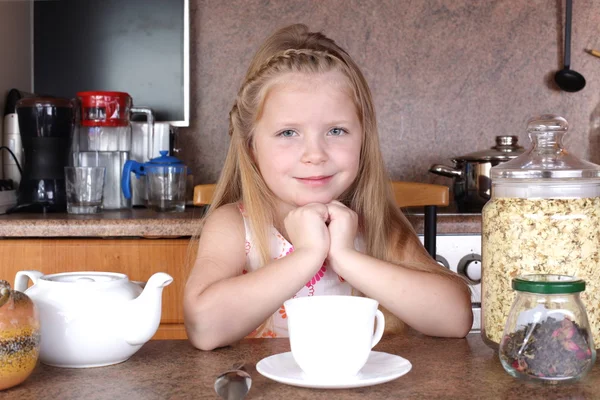 Kleines Mädchen trinkt Tee aus Tasse in Küche — Stockfoto