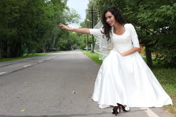 Noiva fugitiva engate-caminhadas em uma estrada — Fotografia de Stock