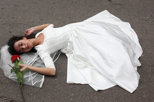 Beautiful bride laying on a road — Stock Photo, Image