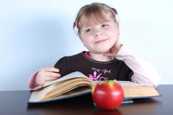 Маленькая девочка с яблоком и книгами — стоковое фото