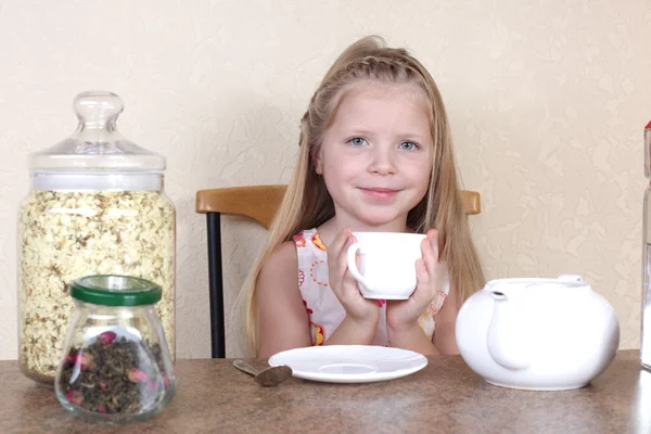 Menina bebe chá de xícara na cozinha — Fotografia de Stock