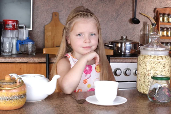 Little girl drinks tea from cup at kitchen — Stock Photo, Image