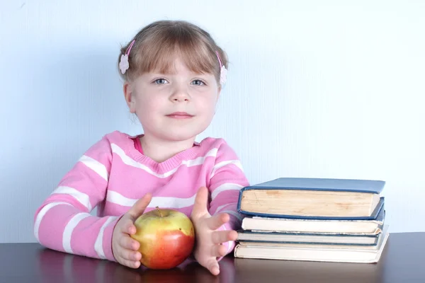 Liten flicka med äpple och böcker — Stockfoto