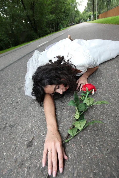 Beautiful bride laying on a road — Stock Photo, Image