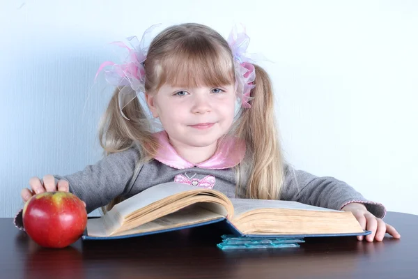 Маленька дівчинка з яблуком і книгами — стокове фото