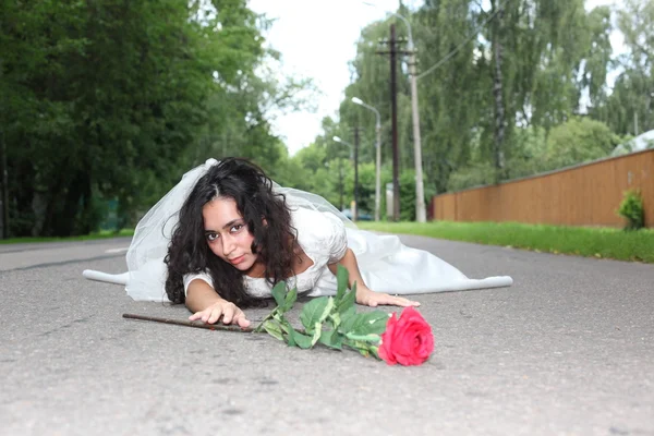 Bride with rose lying on a road — Stock Photo, Image