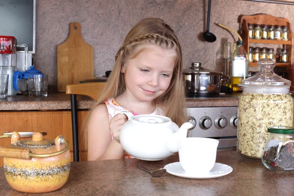 Little girl drinks tea from cup at kitchen — Stock Photo, Image