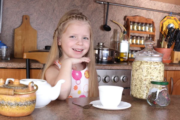 Malá holka pije čaj z poháru v kuchyni — Stock fotografie